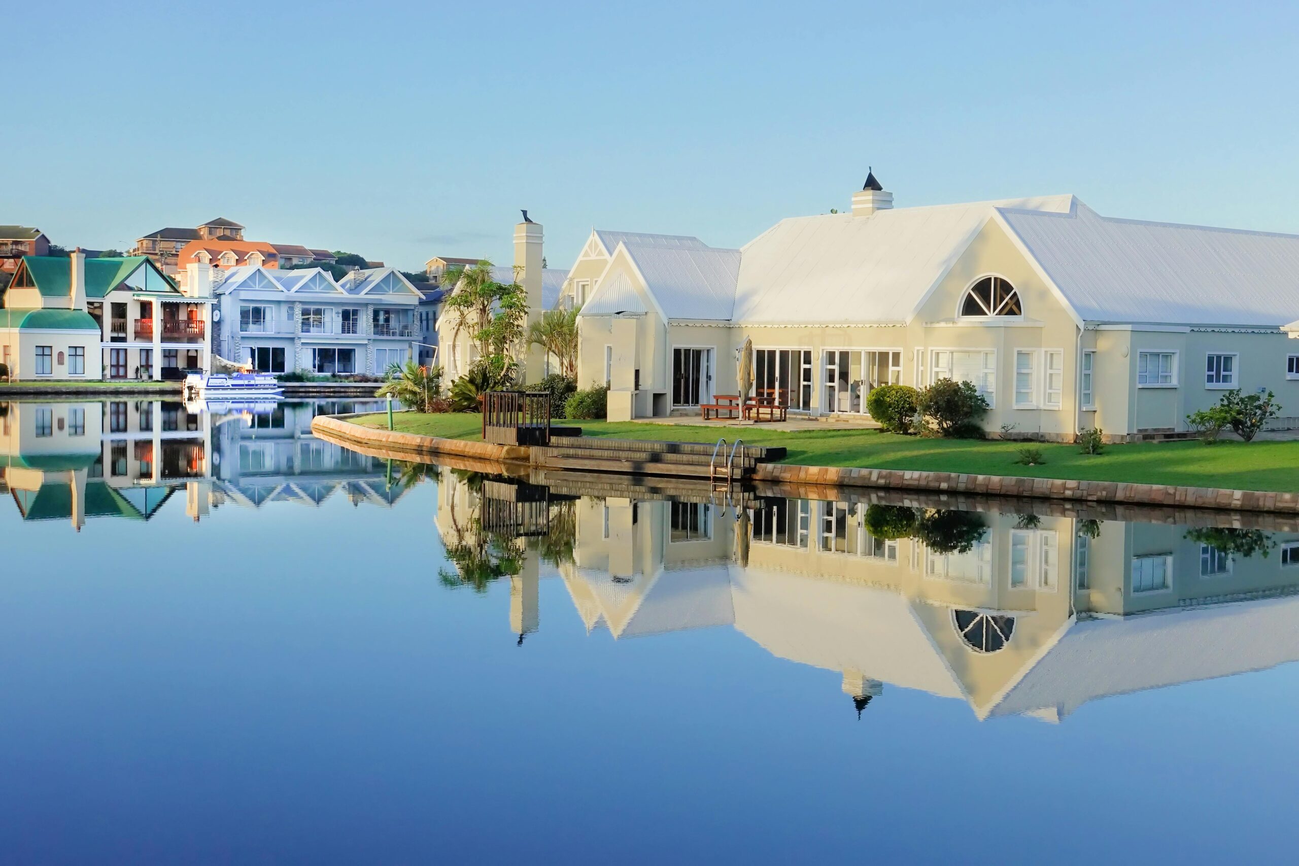 Serene view of elegant waterfront villas with perfect reflection on calm water.